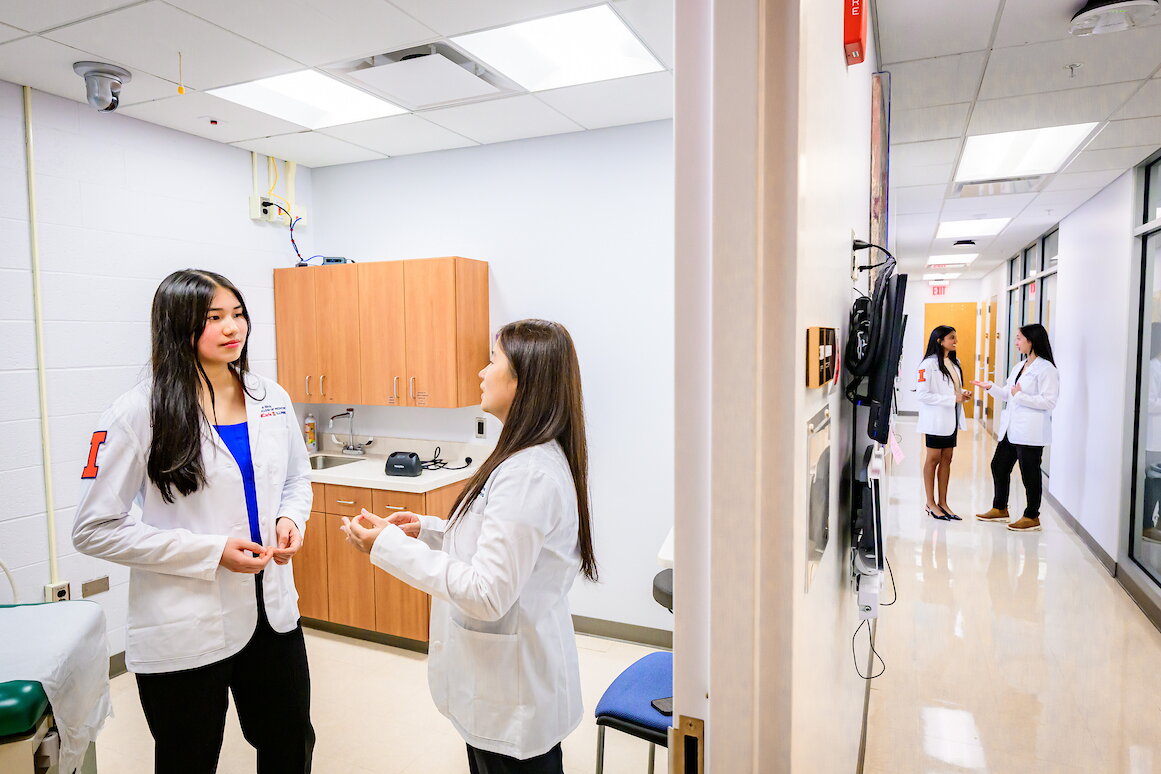 students talking with each in lab coats in a medical facility