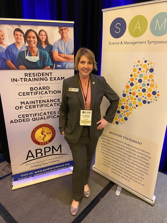 A woman standing in front of two signs at a medical conference