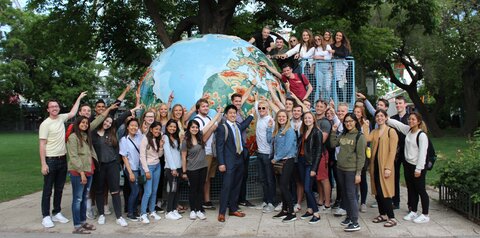 MCB students studying abroad in Vienna gather around a large globe